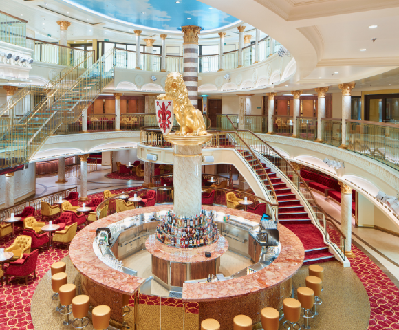 Elegant main area onboard cruise ship with open bar and staircase.