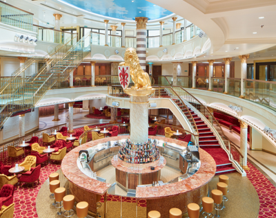 Elegant main area onboard cruise ship with open bar and staircase.
