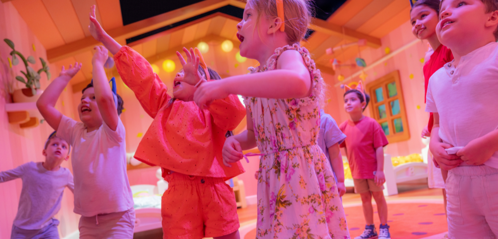 A group of children joyfully dancing and celebrating in a colorful, vibrant room filled with playful decorations.