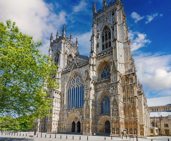 Westminster Abbey stands tall with its detailed Gothic architecture surrounded by greenery.