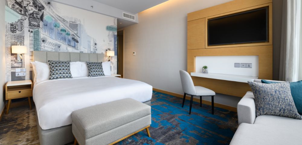 Hotel room with two beds, large windows, and contemporary furnishings.