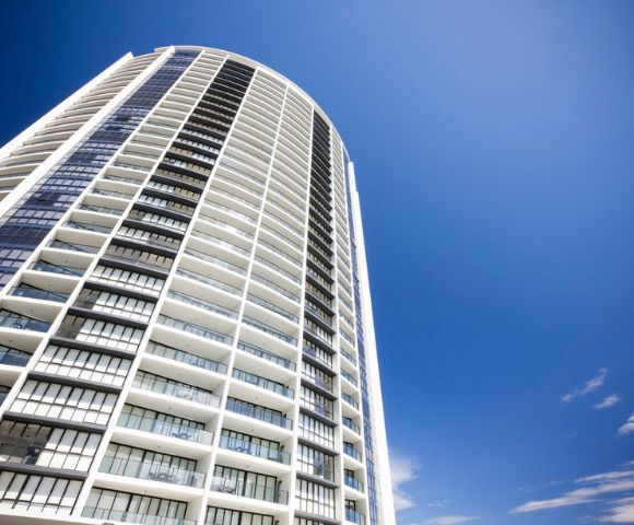 Another close-up of sun loungers beside an infinity-edge pool with a city skyline view.