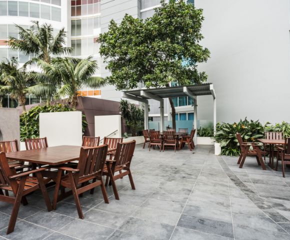 Outdoor dining area surrounded by greenery, with multiple tables and chairs for al fresco dining.