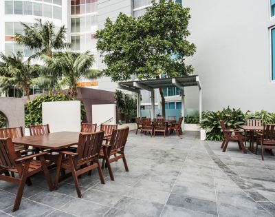 Outdoor dining area surrounded by greenery, with multiple tables and chairs for al fresco dining.