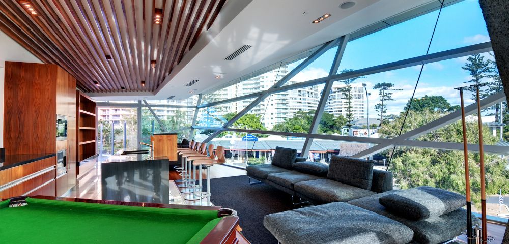 Entertainment room with a pool table and seating area, large windows offering an ocean view.