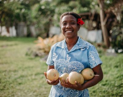 Person holding coconuts and smiling in a grassy area, adding a friendly and welcoming vibe to the resort experience.