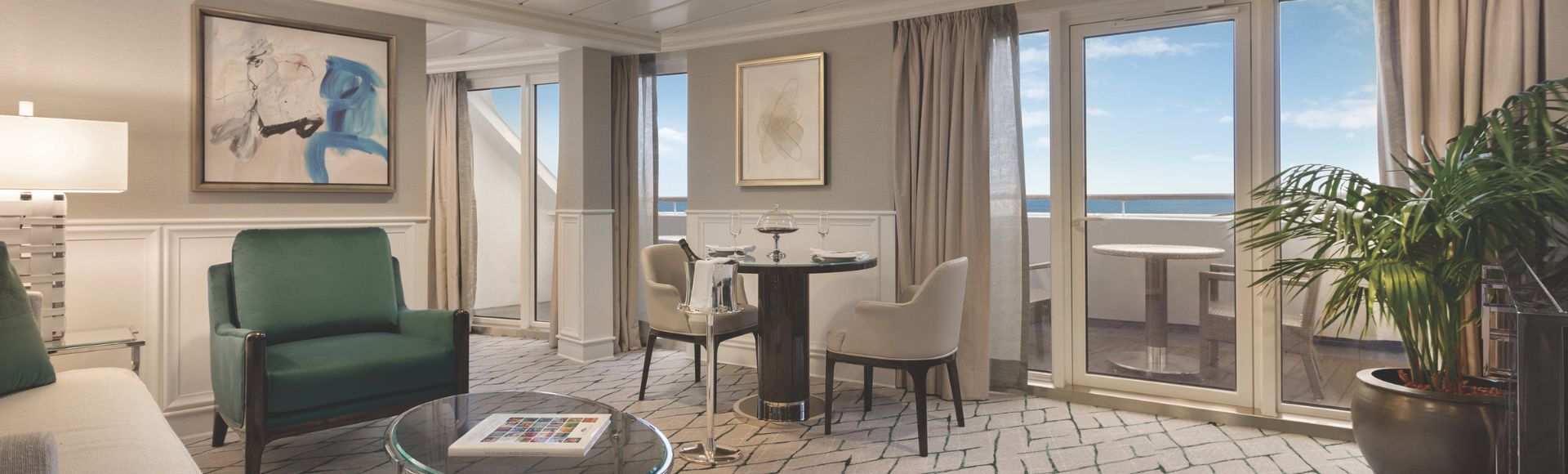 Stylish cruise stateroom featuring a cozy sitting area, dining table, large windows onto balcony with ocean views, and modern decor.