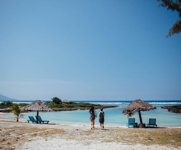 Group of people enjoying the beach—some swimming, others relaxing nearby.