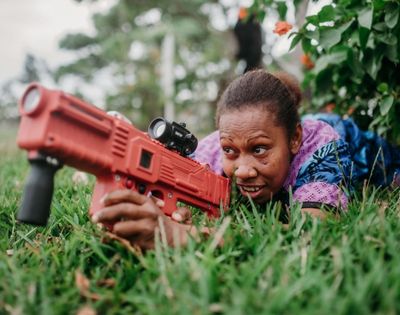 Another close-up of a child aiming a toy dart gun during an outdoor activity.