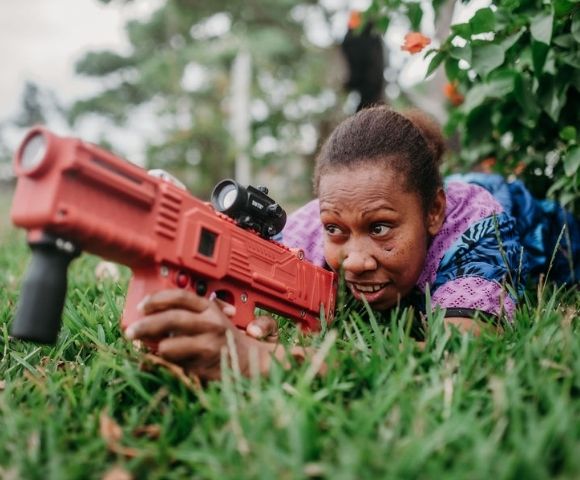 Another close-up of a child aiming a toy dart gun during an outdoor activity.