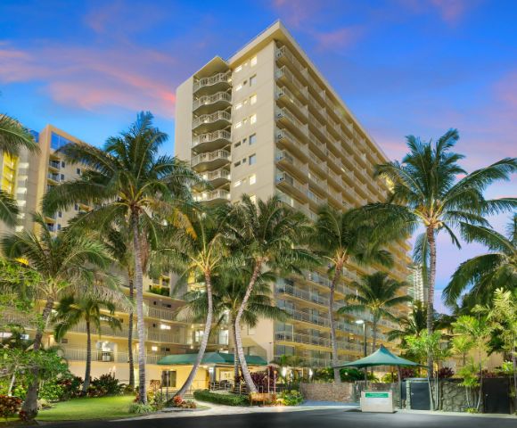 Tall hotel building with palm trees in the foreground.