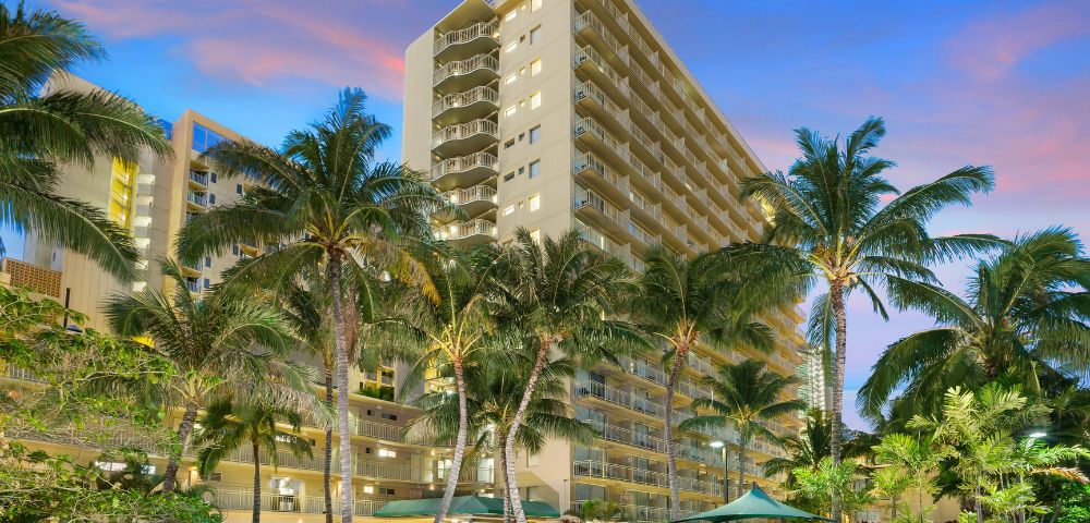 Tall hotel building with palm trees in the foreground.