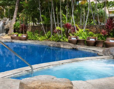 Outdoor swimming pool surrounded by lounge chairs and palm trees