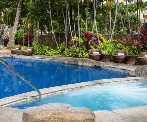 Outdoor swimming pool surrounded by lounge chairs and palm trees