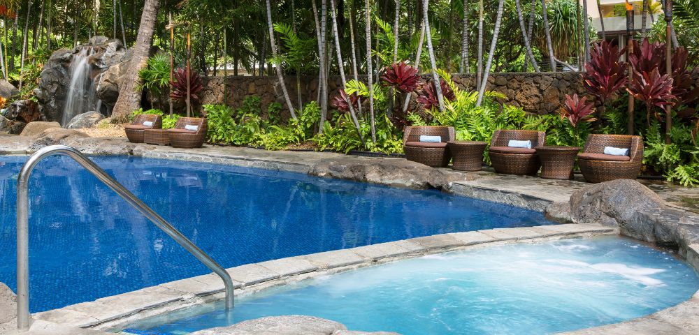 Outdoor swimming pool surrounded by lounge chairs and palm trees
