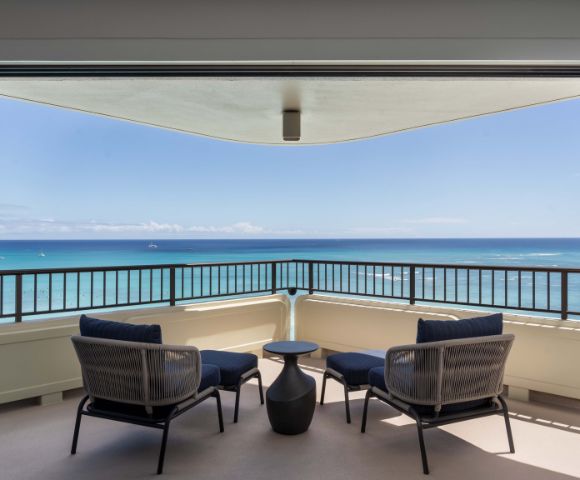 Spacious balcony with two chairs and a small table, offering a clear ocean view at the Moana Surfrider resort.