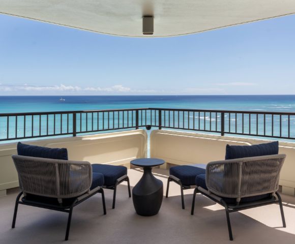 Spacious balcony with two chairs and a small table, offering a clear ocean view at the Moana Surfrider resort.