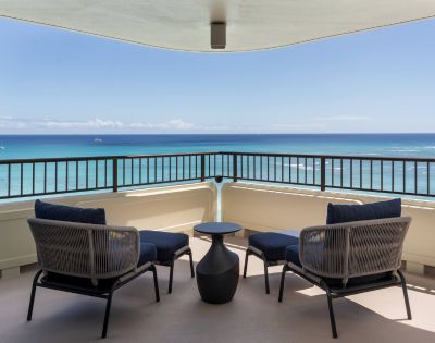 Spacious balcony with two chairs and a small table, offering a clear ocean view at the Moana Surfrider resort.