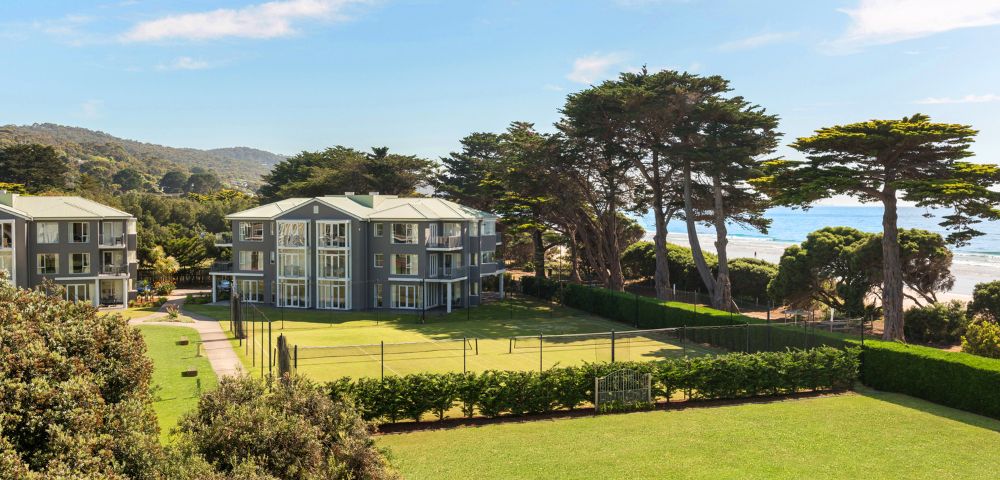 Exterior view of residential buildings with well-maintained lawns and trees in a peaceful setting.