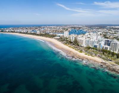 Expansive coastal view featuring a beach, ocean, and numerous high-rise buildings along the shoreline.