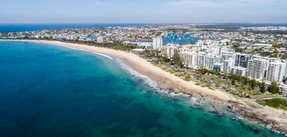 Expansive coastal view featuring a beach, ocean, and numerous high-rise buildings along the shoreline.