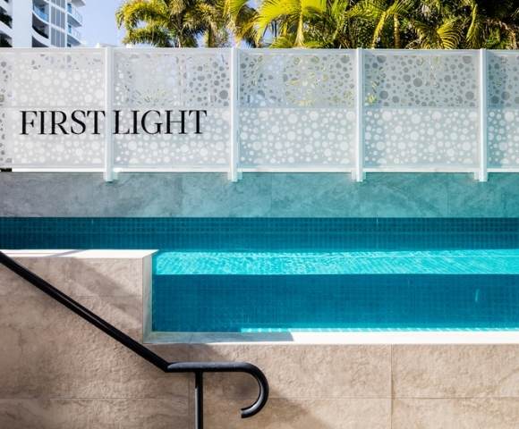 Close-up view of a swimming pool with clear water and steps, adjacent to a wall labeled 'FIRST LIGHT'.