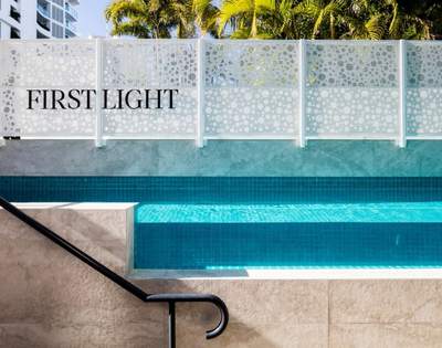 Close-up view of a swimming pool with clear water and steps, adjacent to a wall labeled 'FIRST LIGHT'.
