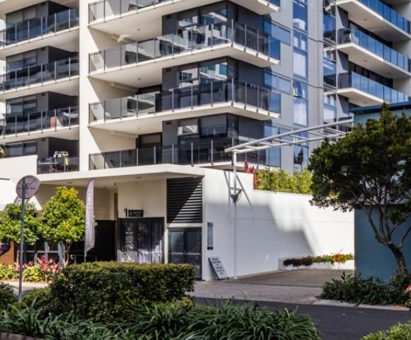 Exterior view of a multi-story residential building surrounded by greenery, highlighting modern architecture and landscaping.