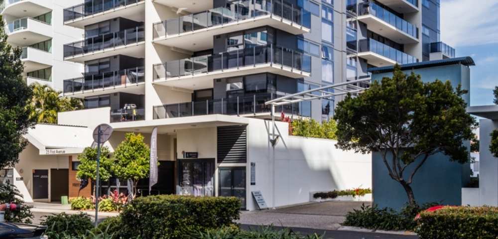 Exterior view of a multi-story residential building surrounded by greenery, highlighting modern architecture and landscaping.