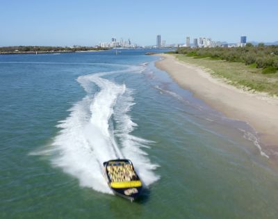 Passengers gripping seats on a fast-moving jet boat during a sharp turn.