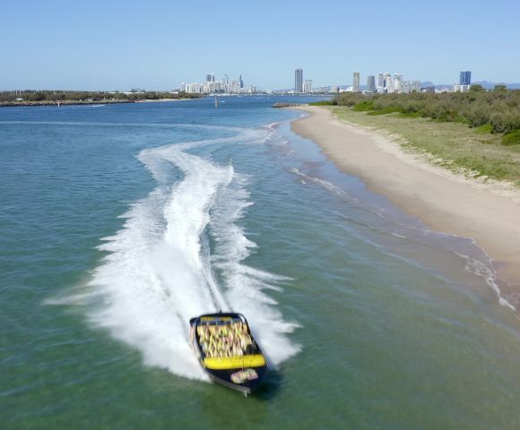 Passengers gripping seats on a fast-moving jet boat during a sharp turn.