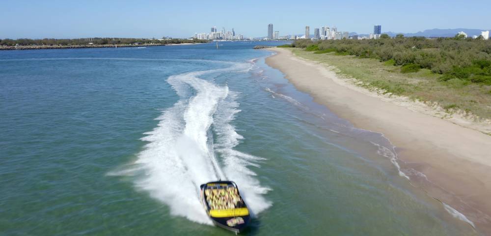 Passengers gripping seats on a fast-moving jet boat during a sharp turn.