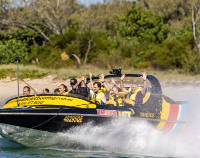 Jet boat gliding over water with scenic background and visible branding.