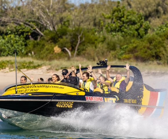 Jet boat gliding over water with scenic background and visible branding.