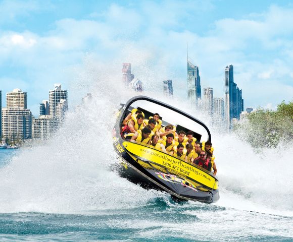 Jet boat performing stunts near towering city buildings, showcasing urban adventure.