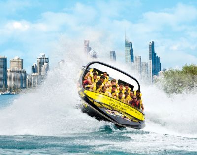 Jet boat performing stunts near towering city buildings, showcasing urban adventure.