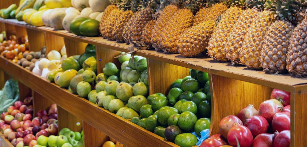 Rows of fresh fruits on wooden shelves in a market display.