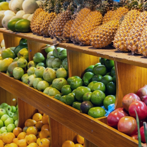 Rows of fresh fruits on wooden shelves in a market display.