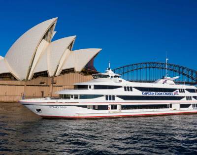Sydney Opera House and a large yacht on calm waters under clear blue skies