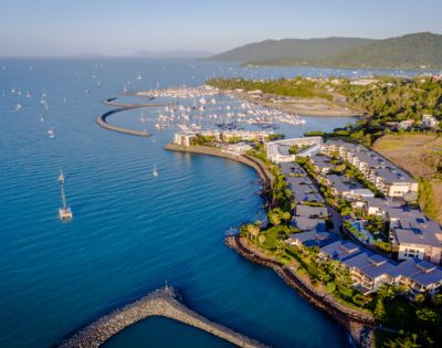Aerial shot of coastal housing development along calm waters with boats.