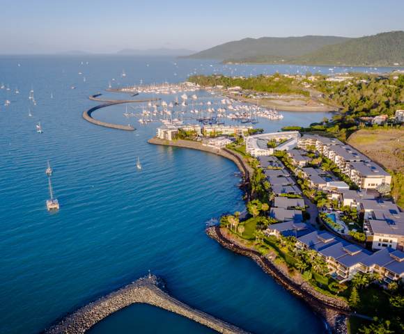 Aerial shot of coastal housing development along calm waters with boats.