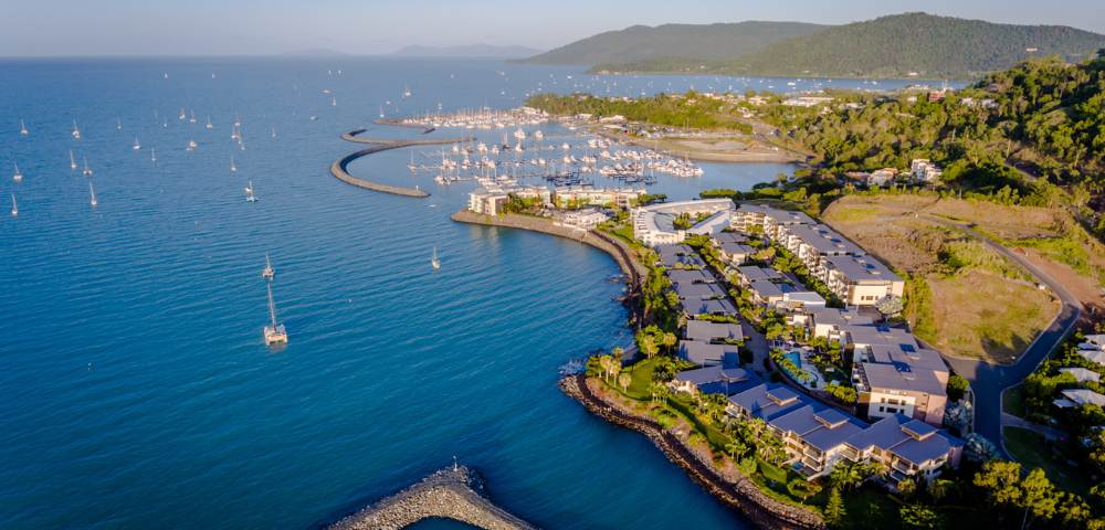 Aerial shot of coastal housing development along calm waters with boats.