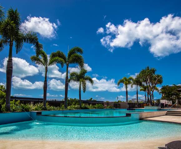 Luxurious swimming pool surrounded by palm trees under a clear blue sky.