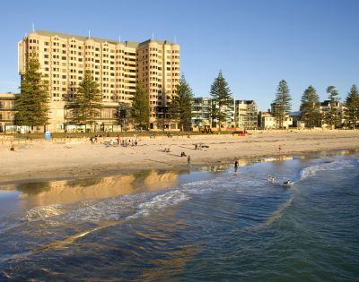 A beachfront hotel with palm trees under a clear blue sky.