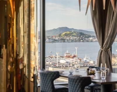 View from a hotel window overlooking a serene landscape with water and hills.