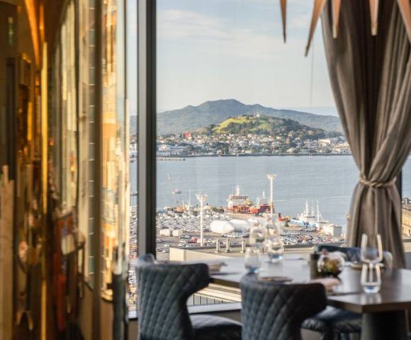 View from a hotel window overlooking a serene landscape with water and hills.