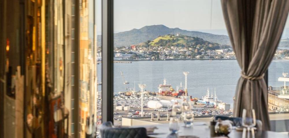 View from a hotel window overlooking a serene landscape with water and hills.