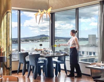 Hotel dining area with refined table settings and large windows overlooking the city.