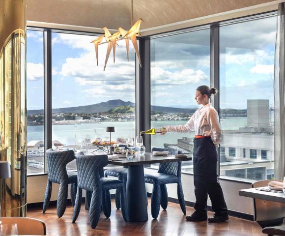 Hotel dining area with refined table settings and large windows overlooking the city.