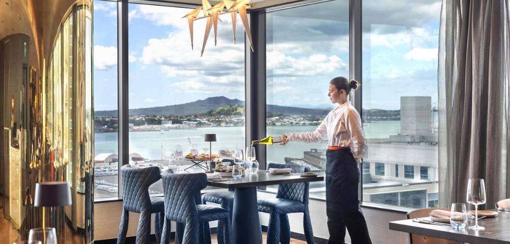 Hotel dining area with refined table settings and large windows overlooking the city.